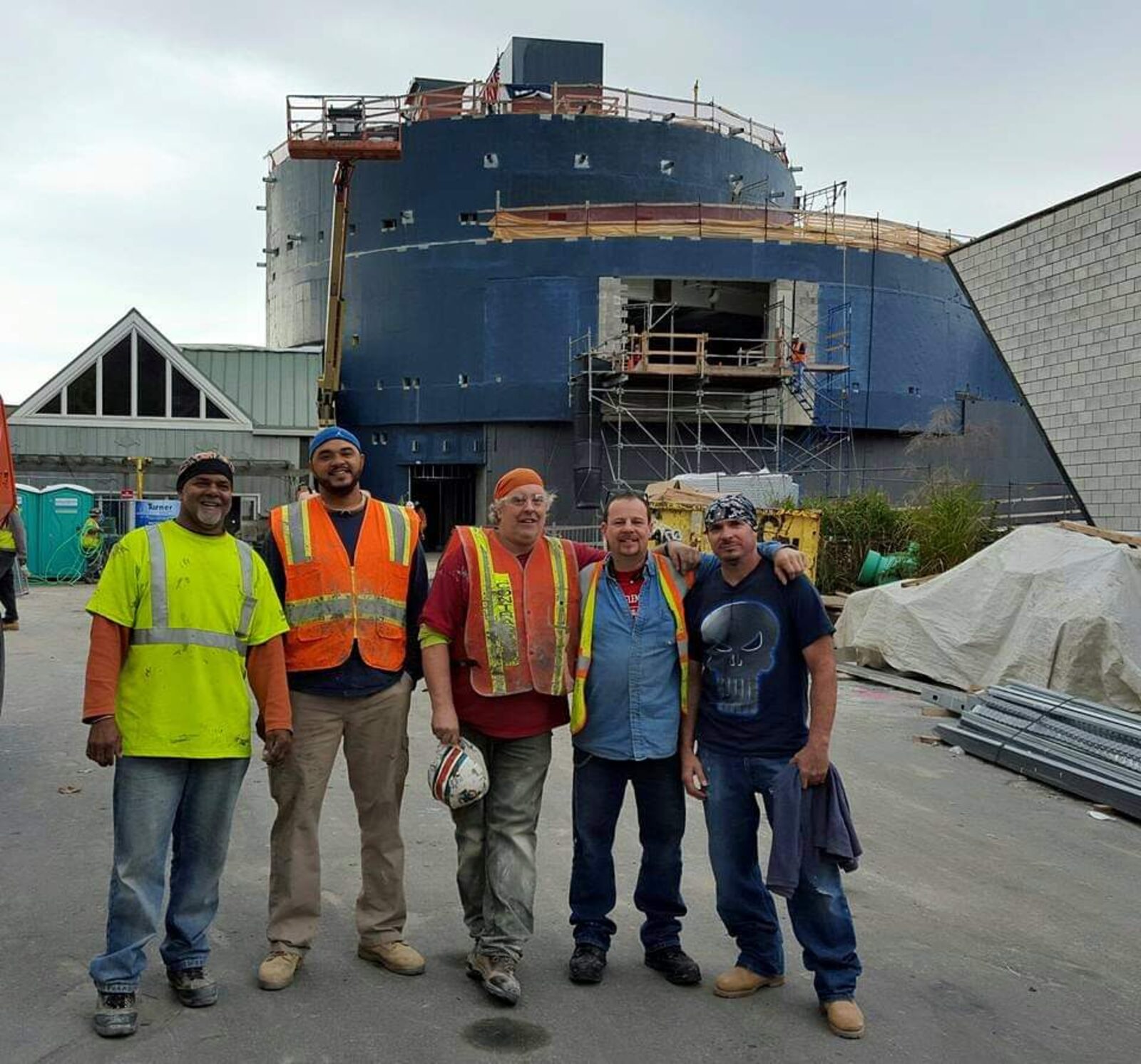 A union sheet metal crew posing in front of a large industrial structure under construction